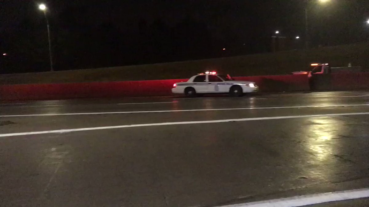 There are police officers with their lights on on US 35 East and West at James H McGee Blvd. the road is partially flooded. 