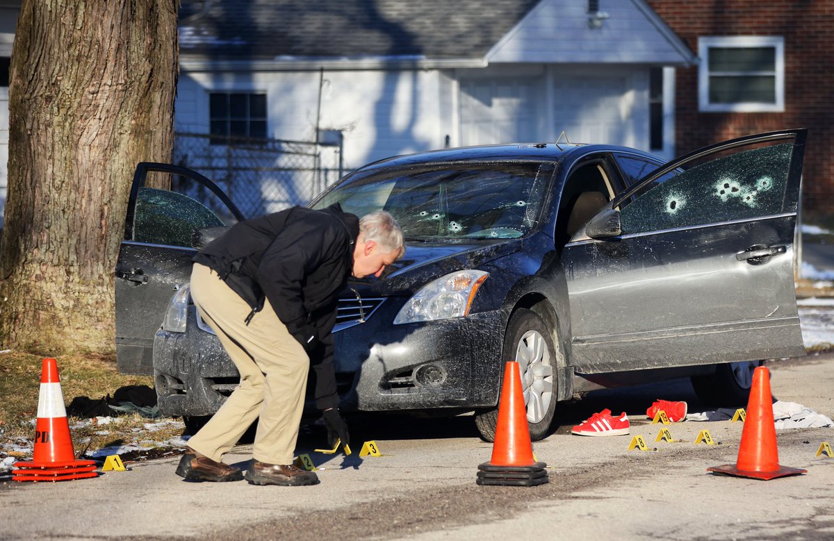 An investigator places evidence markers at the scene of a shooting on Christie Street near Merrimac Boulevard in Toledo on Saturday